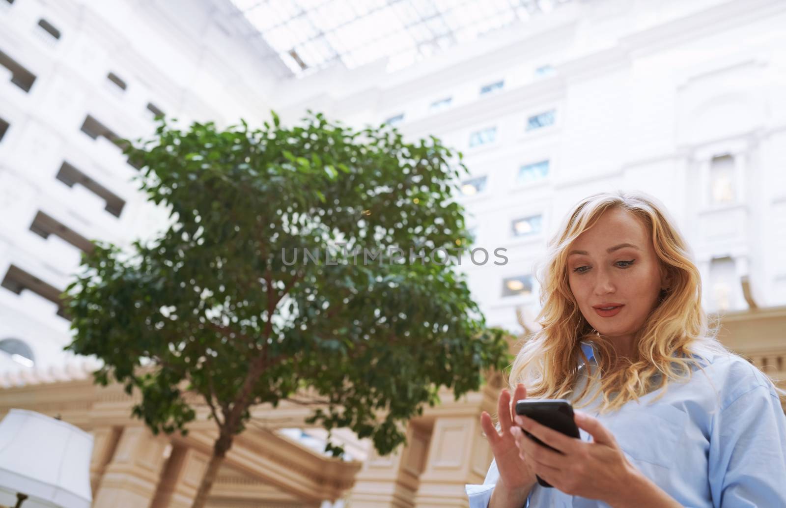 Businesswoman using smartphone in the modern bank lobby by Novic