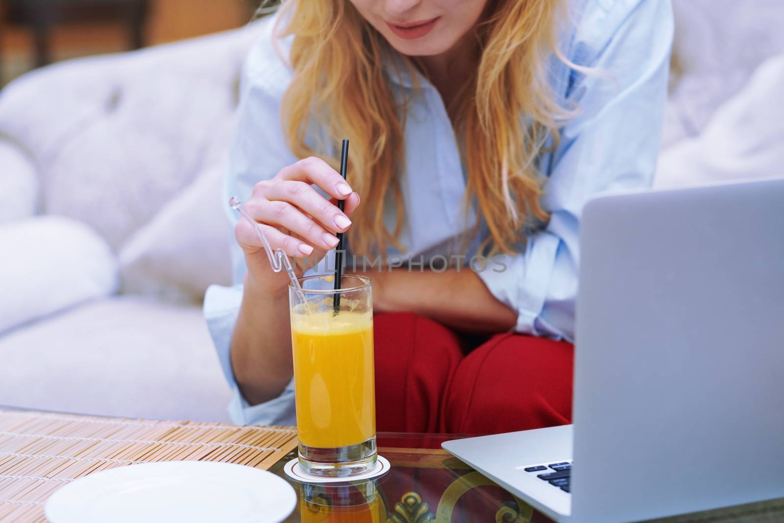 Woman relaxing at the hotel lobby and blogging via laptop by Novic