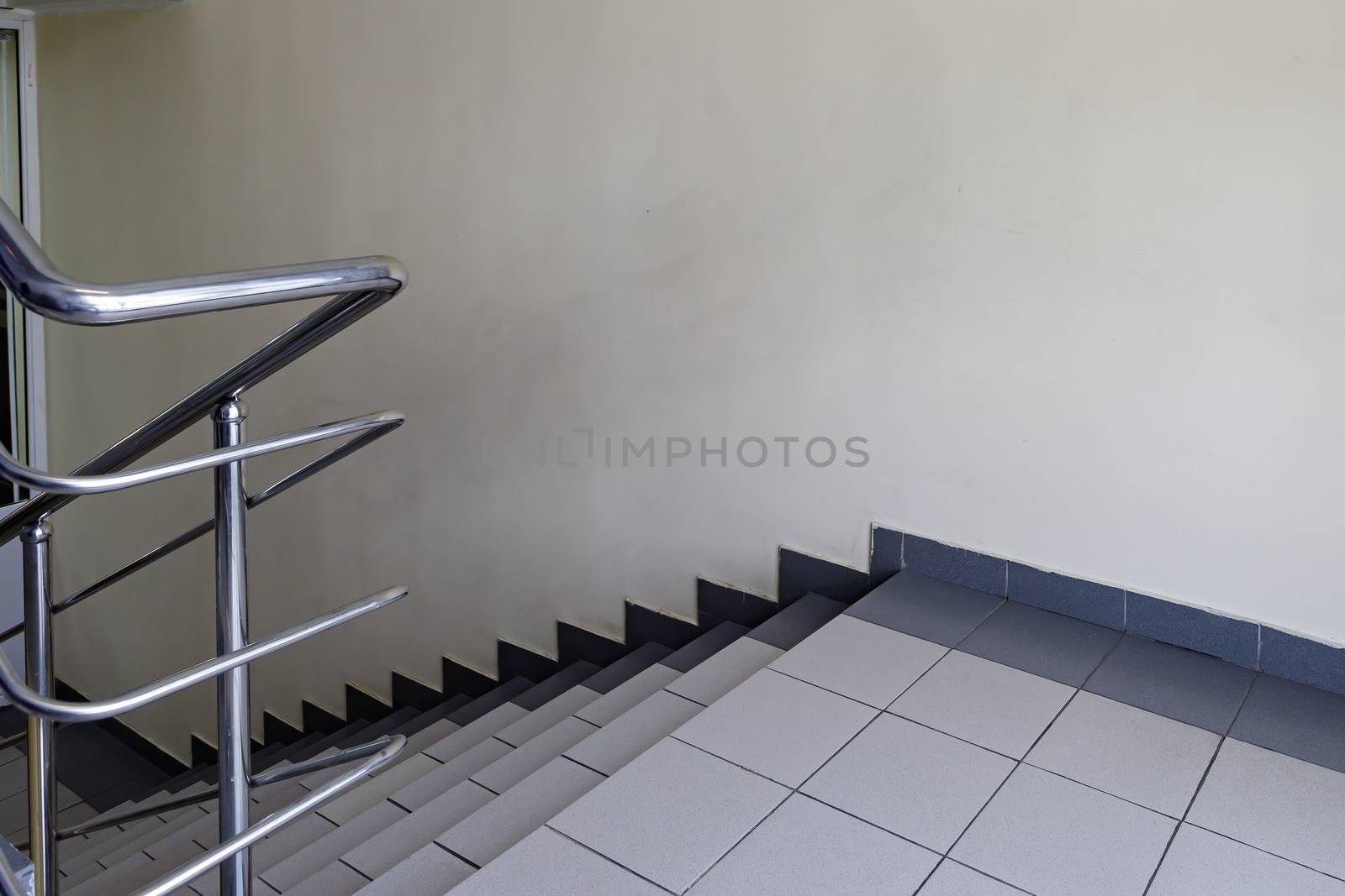 The concept of the interior of an urban building. Photo of a staircase with metal railing between floors.