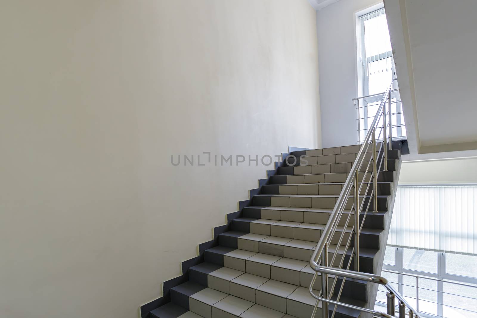 The concept of the interior of an urban building. Photo of a staircase with metal railing between floors.