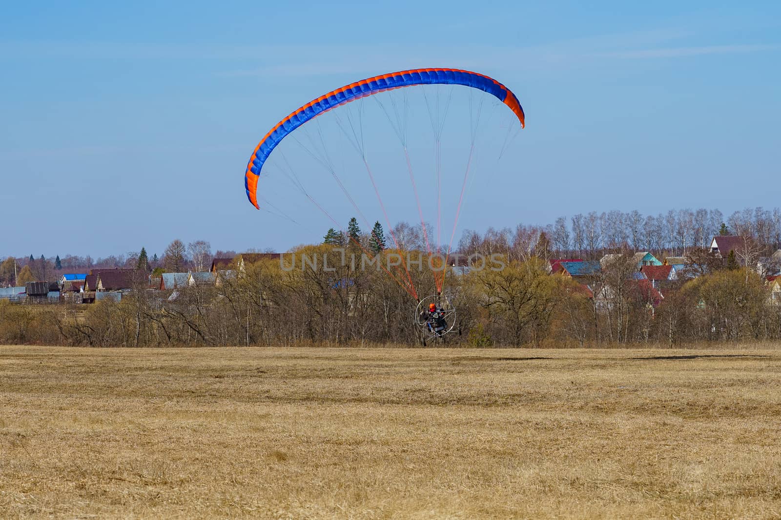 paraglider begins to take off over the field on a sunny day by VADIM