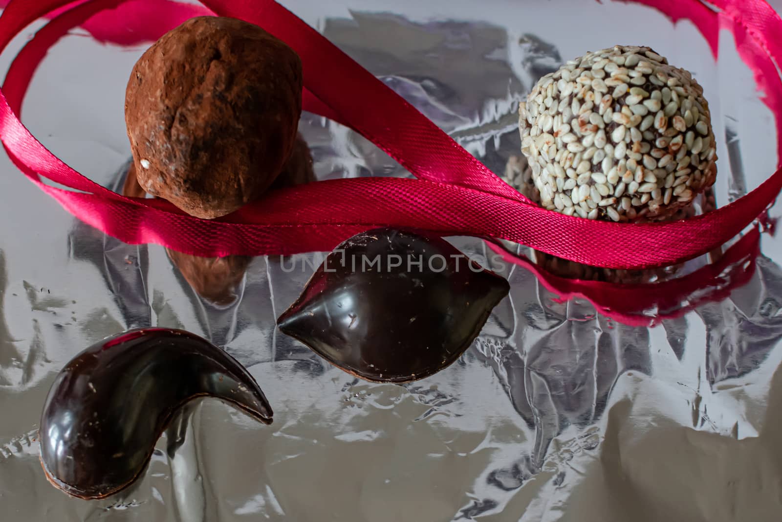 Hand-dipped, chocolate candy, also know as chocolate bon-bons, lay on a silver foil background