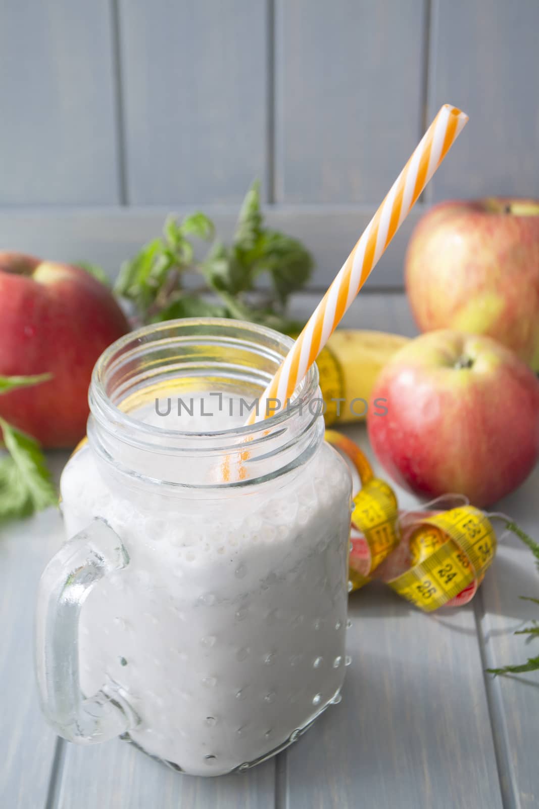 Smoothie of yogurt, nettle, apple, banana and herbs on a light table. Vertical image