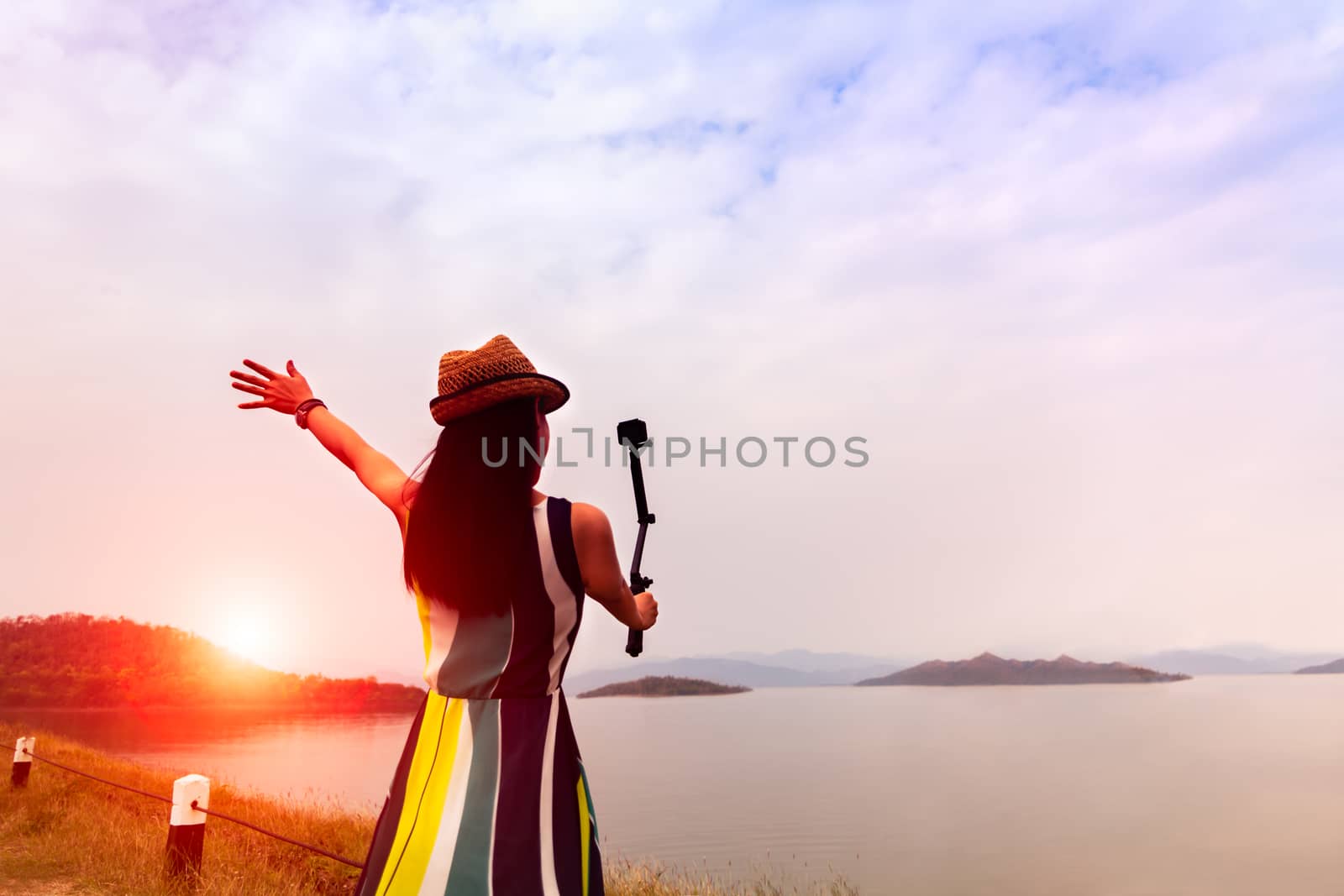 traveler woman enjoy take a selfie at beautiful sunset on the lake with mountains on background