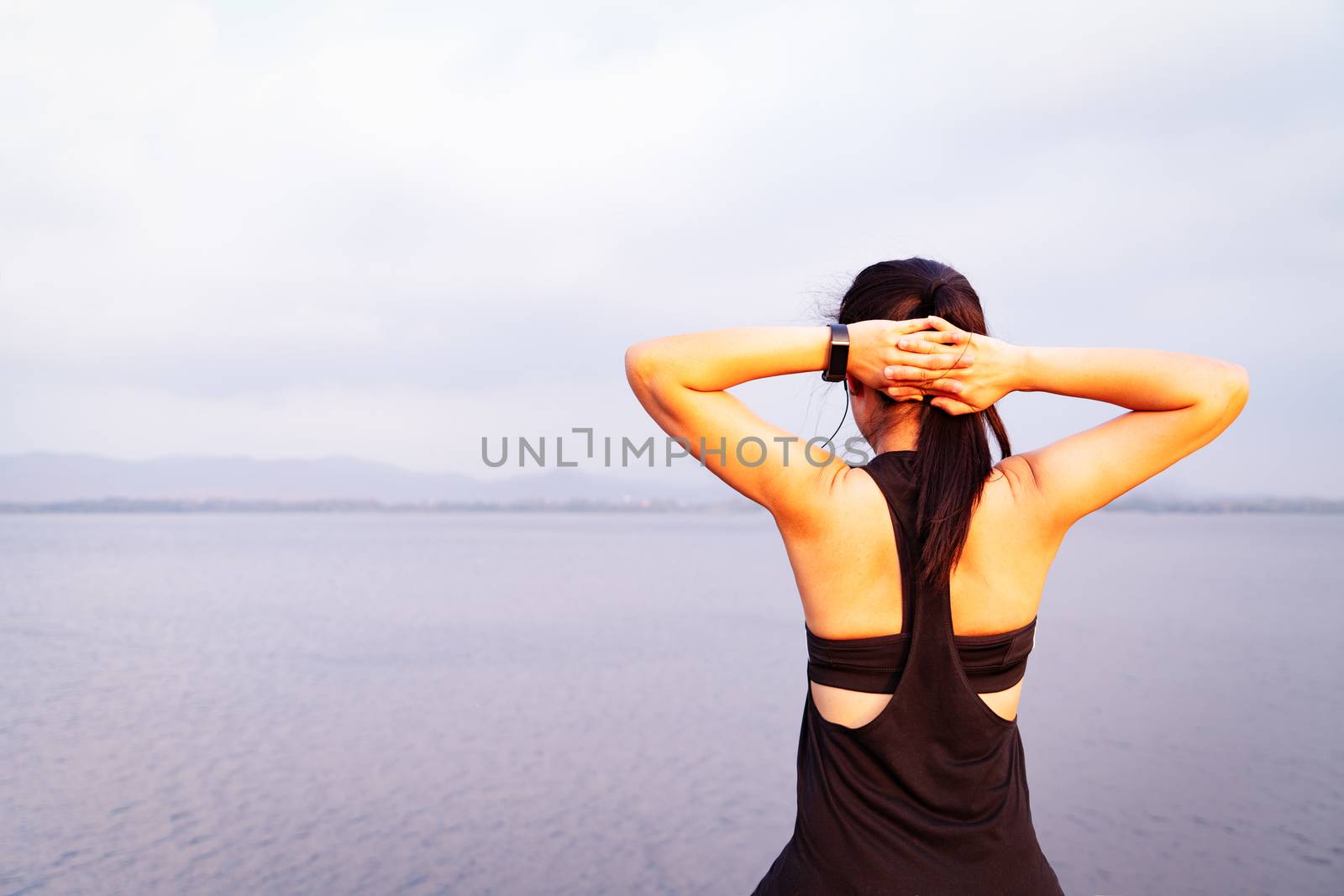 Young athlete woman streching near the lake outdoor, asian Fitness walking and exercise in sunset scene. wellness and sport concepts