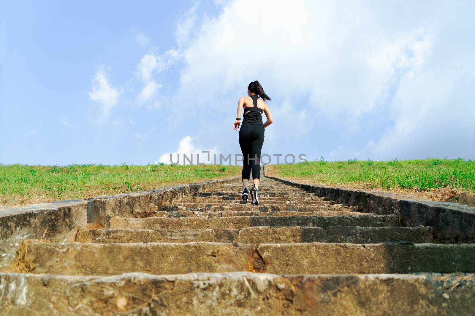 young sport woman running outdoor upstairs on blue sky