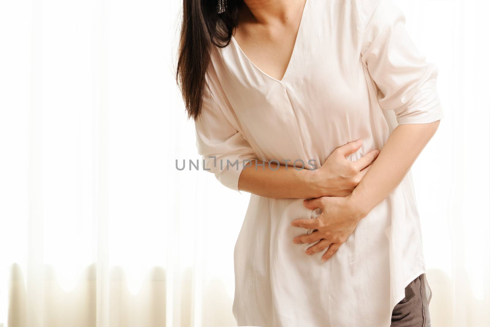 Young woman suffering from abdominal pain feeling stomachache, symptom of pms on white background