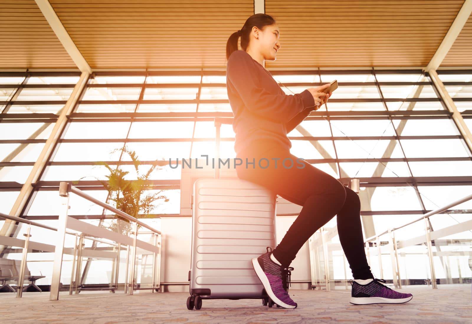 Asia woman using mobile phone while waiting flight in modern terminal