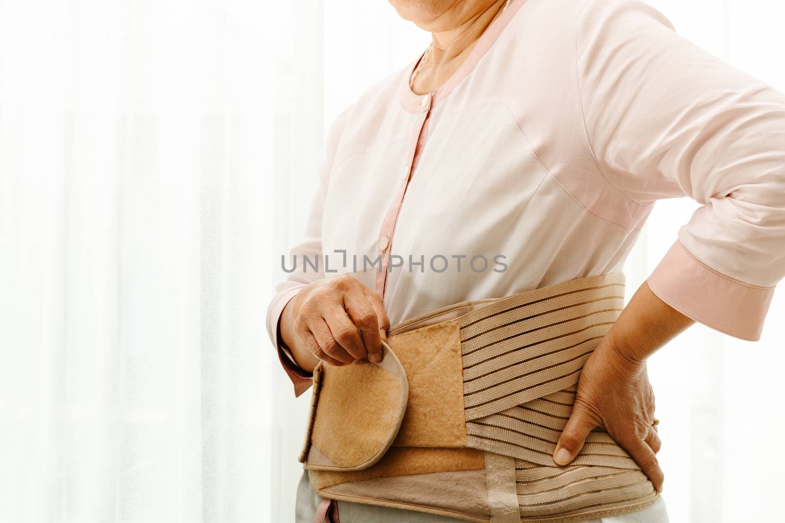 back pain, senior woman wearing back support belt on white background