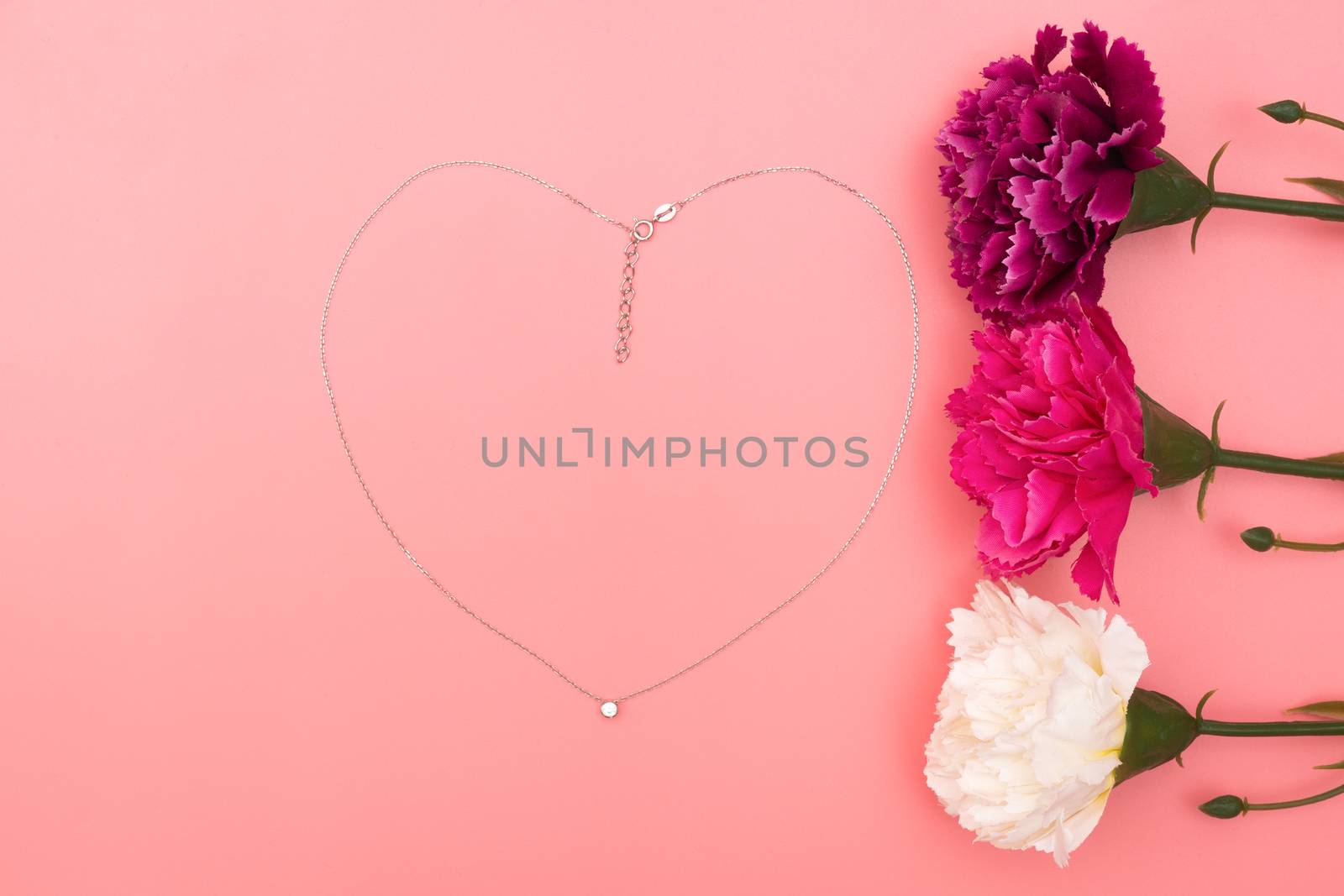 International Womens Day with flowers and heart shape necklace on pink background