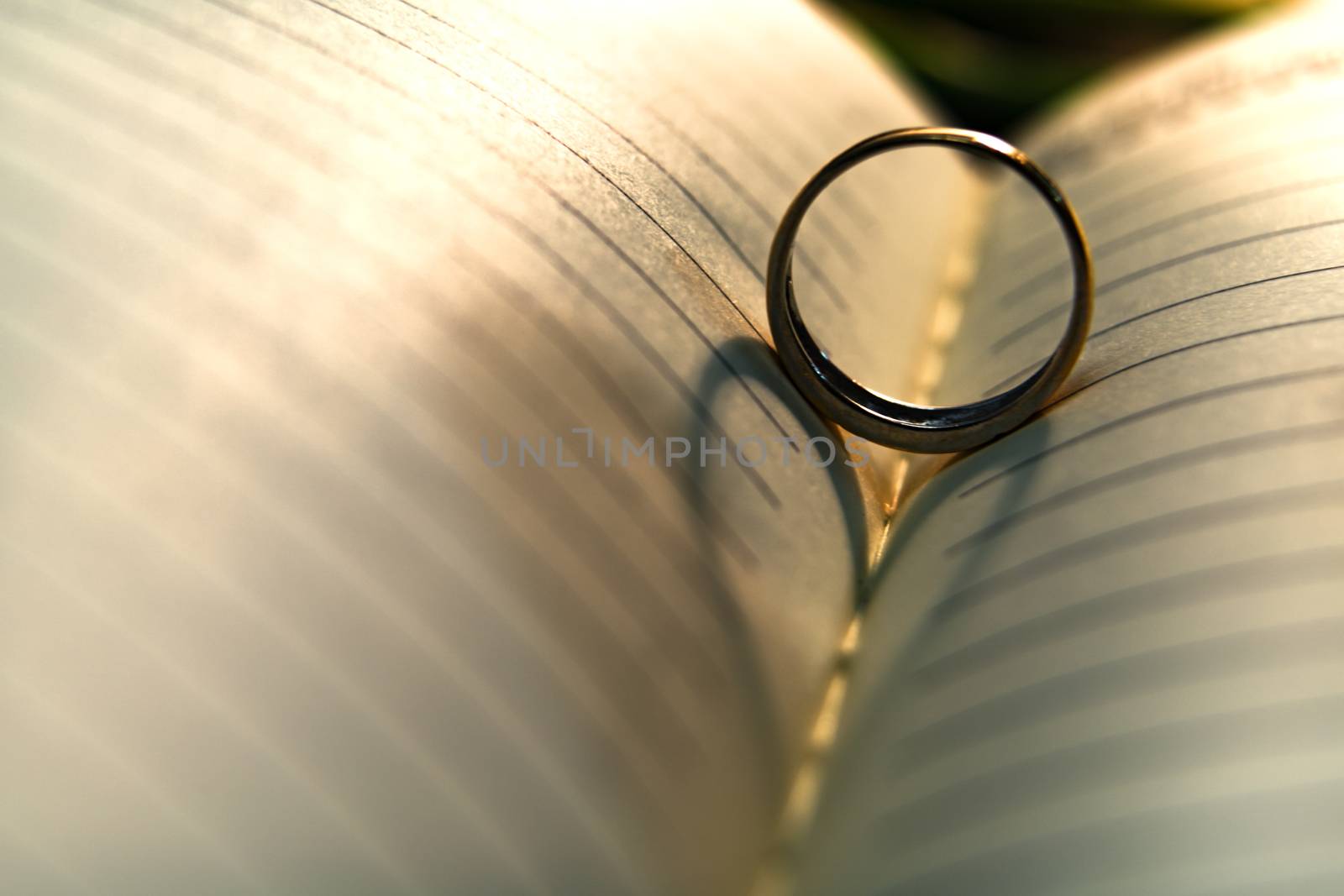 Abstract background of heart shadow of wedding ring casting on the book page