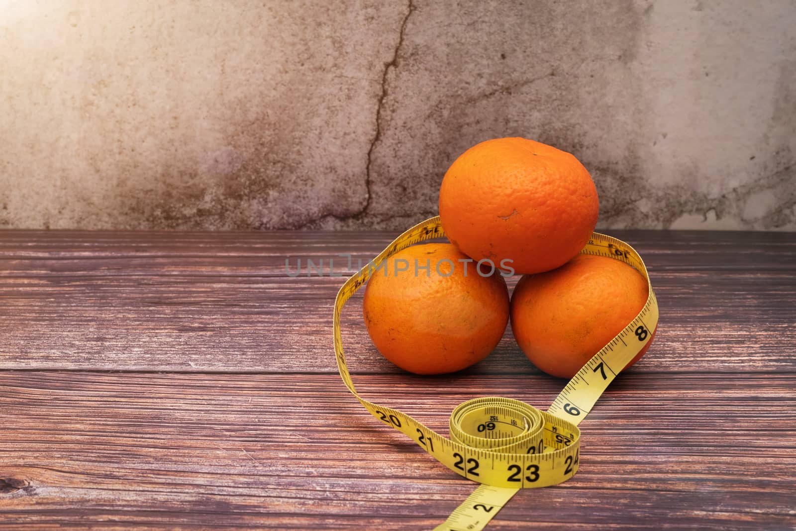 Fresh fruit for diet and measuring tape on wooden table. Concept of diet and healthy lifestyle