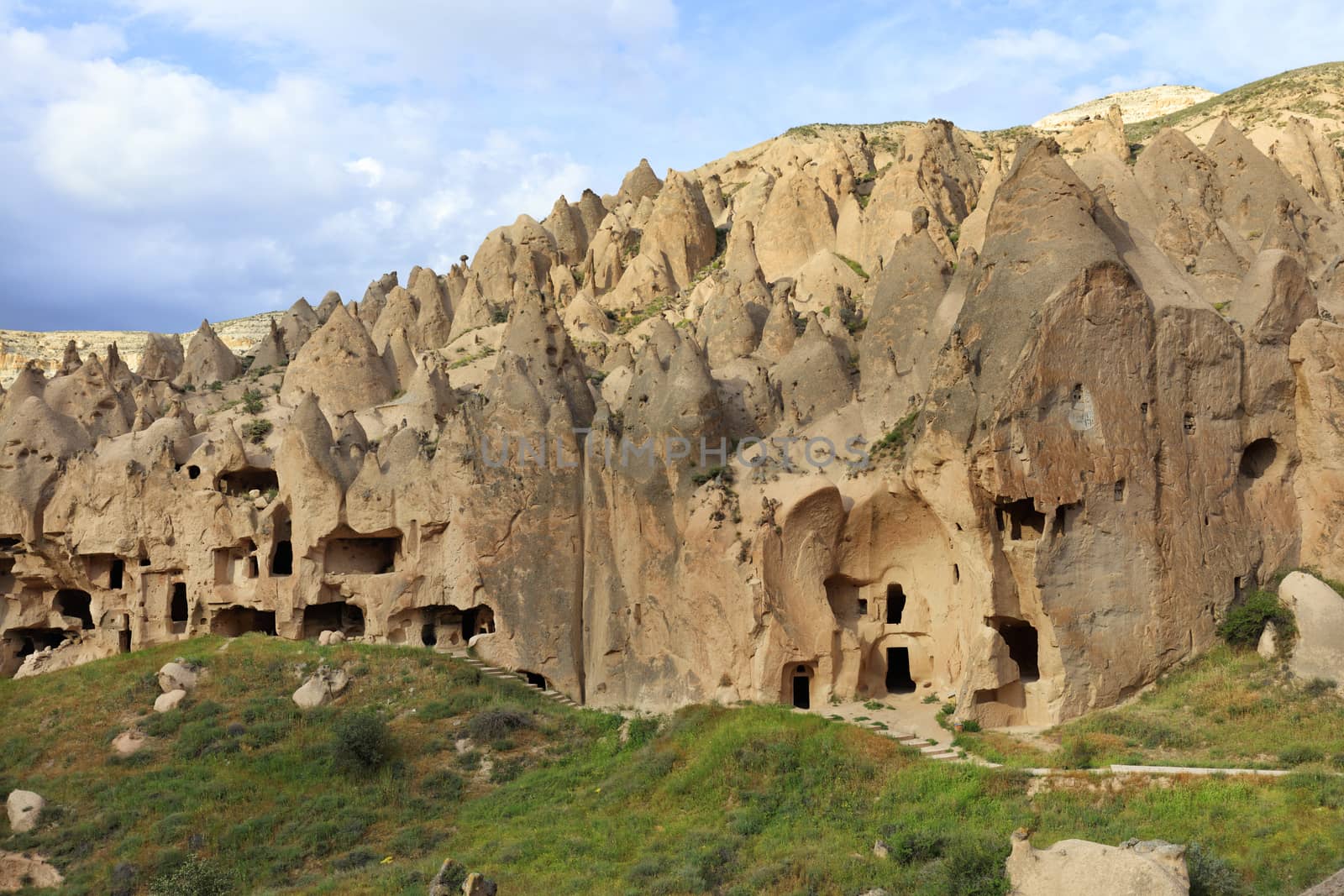 Old antique residential caves on the background of the conical ridges of Cappadocia and the blue cloudy sky