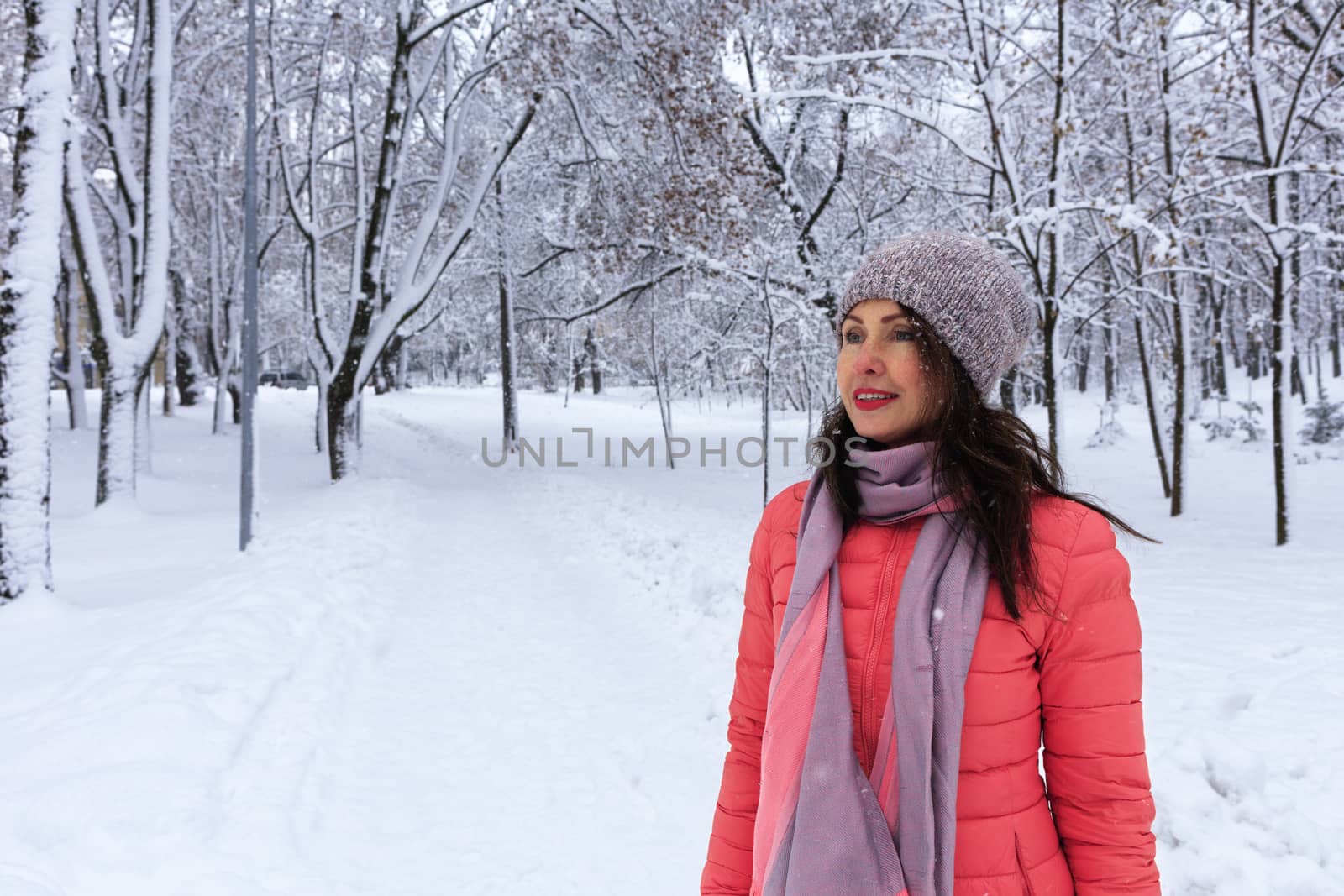 Waist-shot of a happy and stylish beautiful woman in a bright coral jacket, smiling and enjoying a winter day. by Sergii