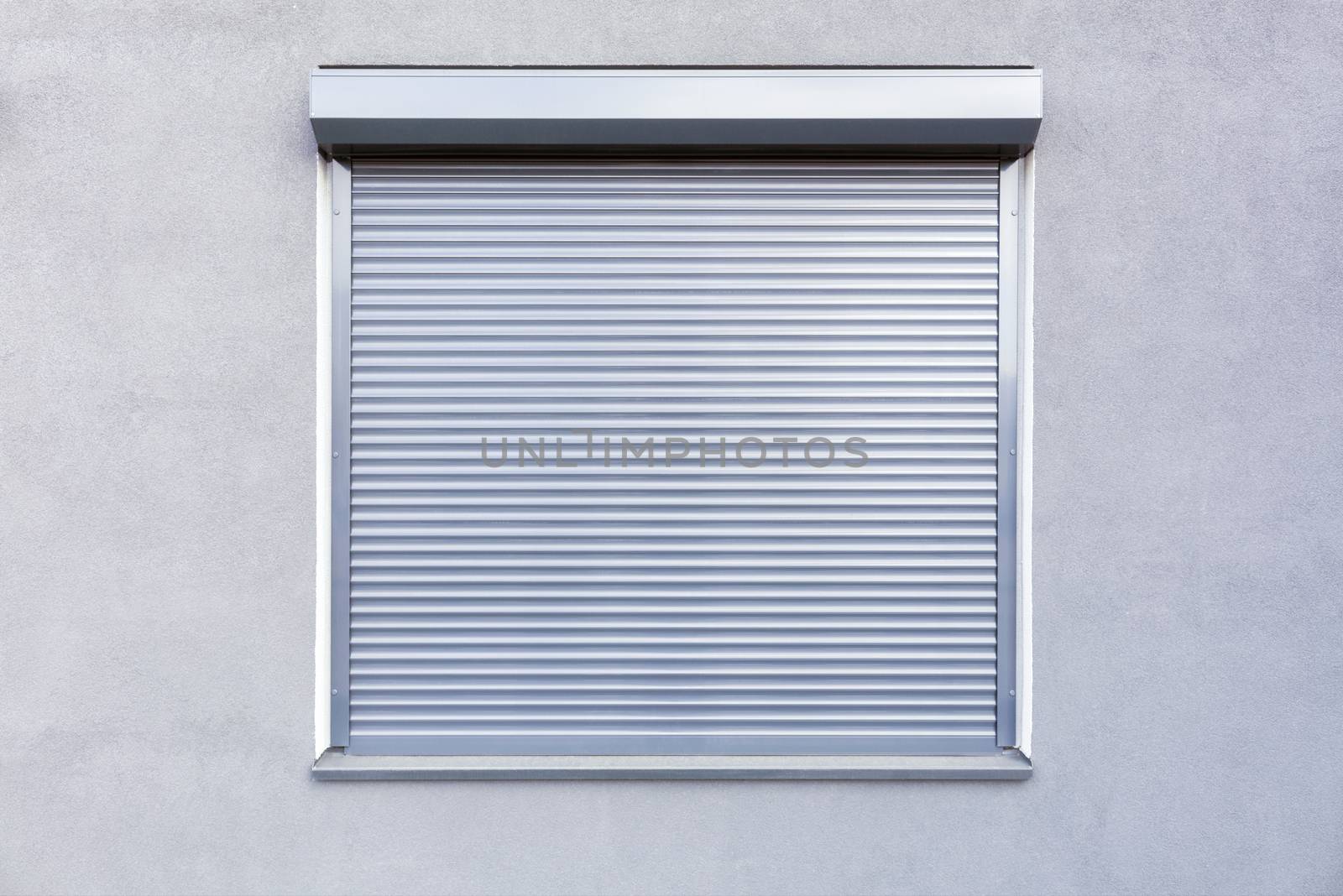 Light gray metal blinds on the windows of the facade of the house.