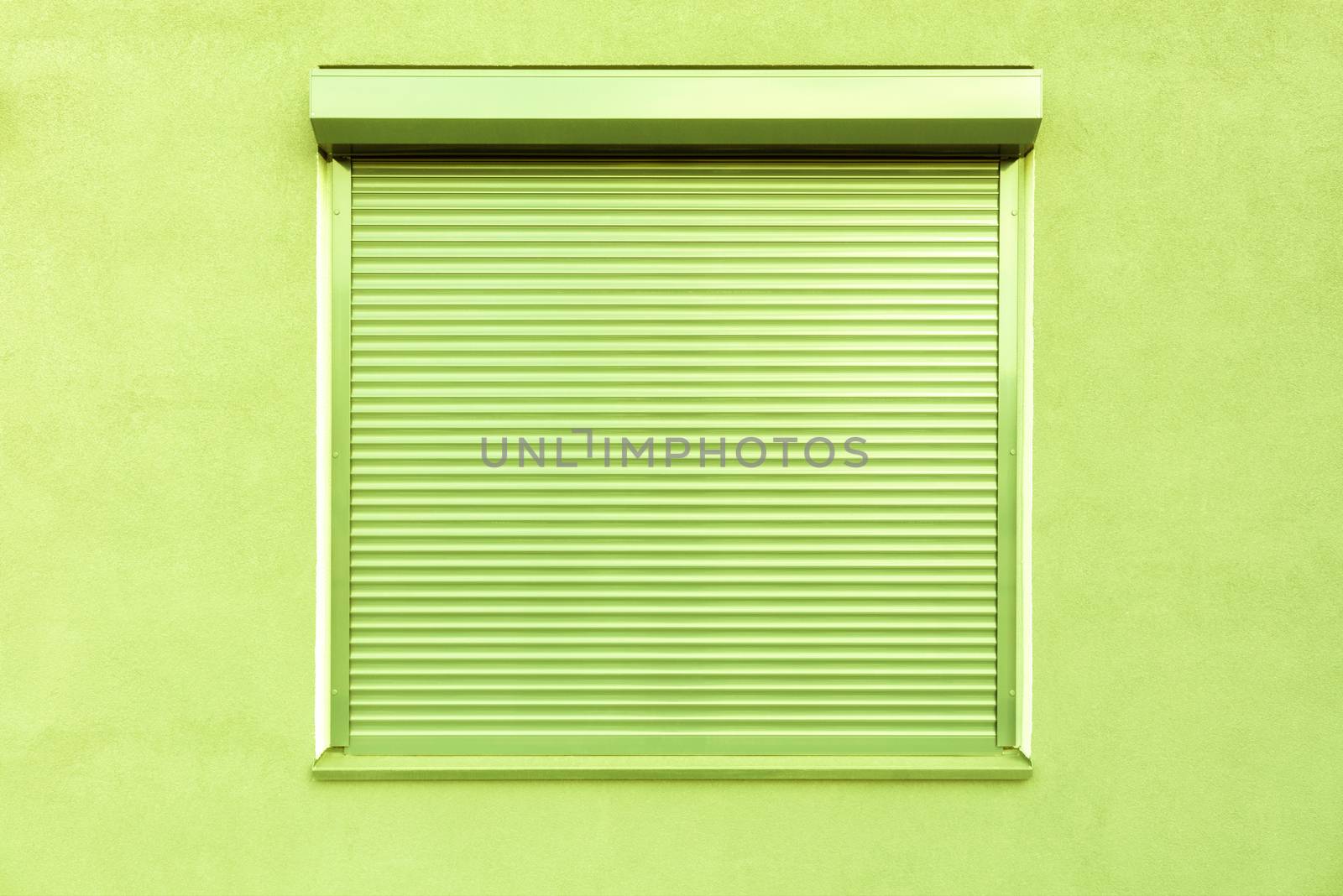 Light green metal blinds on the windows of the facade of the house.