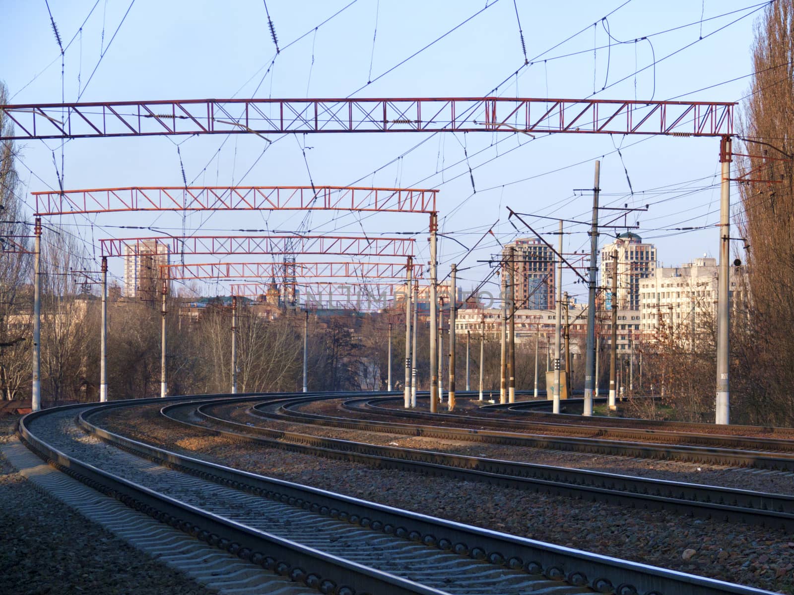 The prospect of many multi-lane railways for electric trains with overhead power lines in the early spring morning, high-rise buildings in the background.