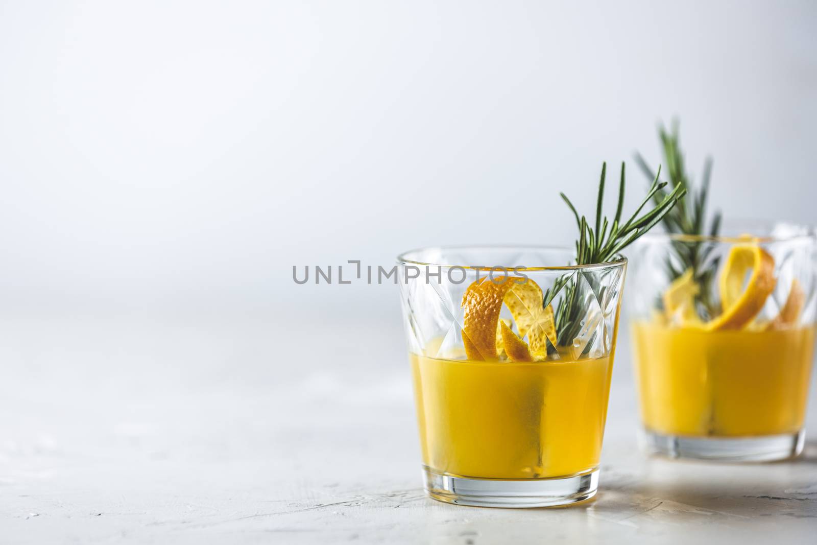 Two glasses of honey bourbon cocktail with rosemary simple syrup or homemade whiskey sour cocktail drink with orange and rosemary decoration orange peel, jar of honey and bartender tools