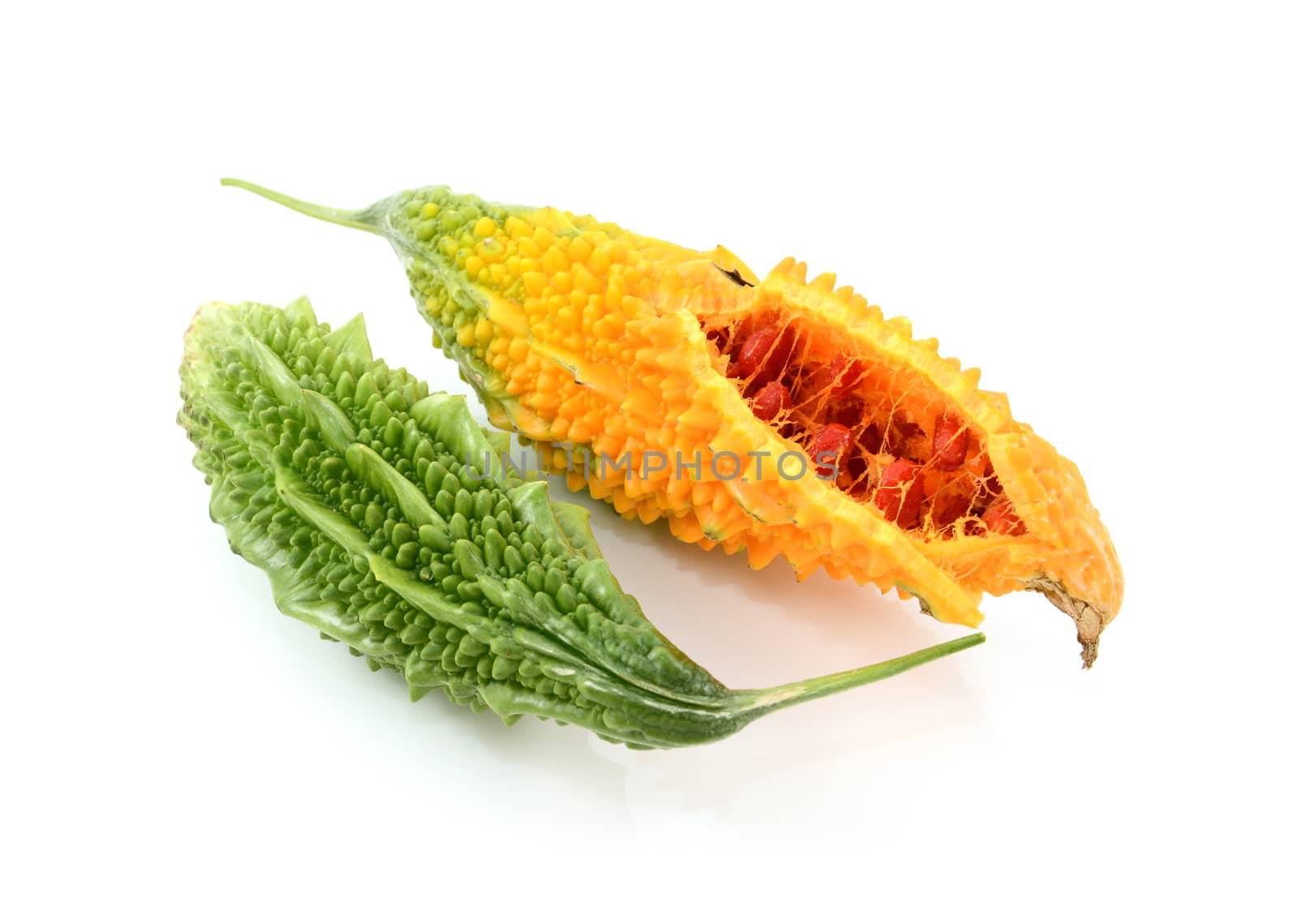 Two ripe bitter melons - green and whole, and orange, split open with red seeds inside, isolated on a white background 