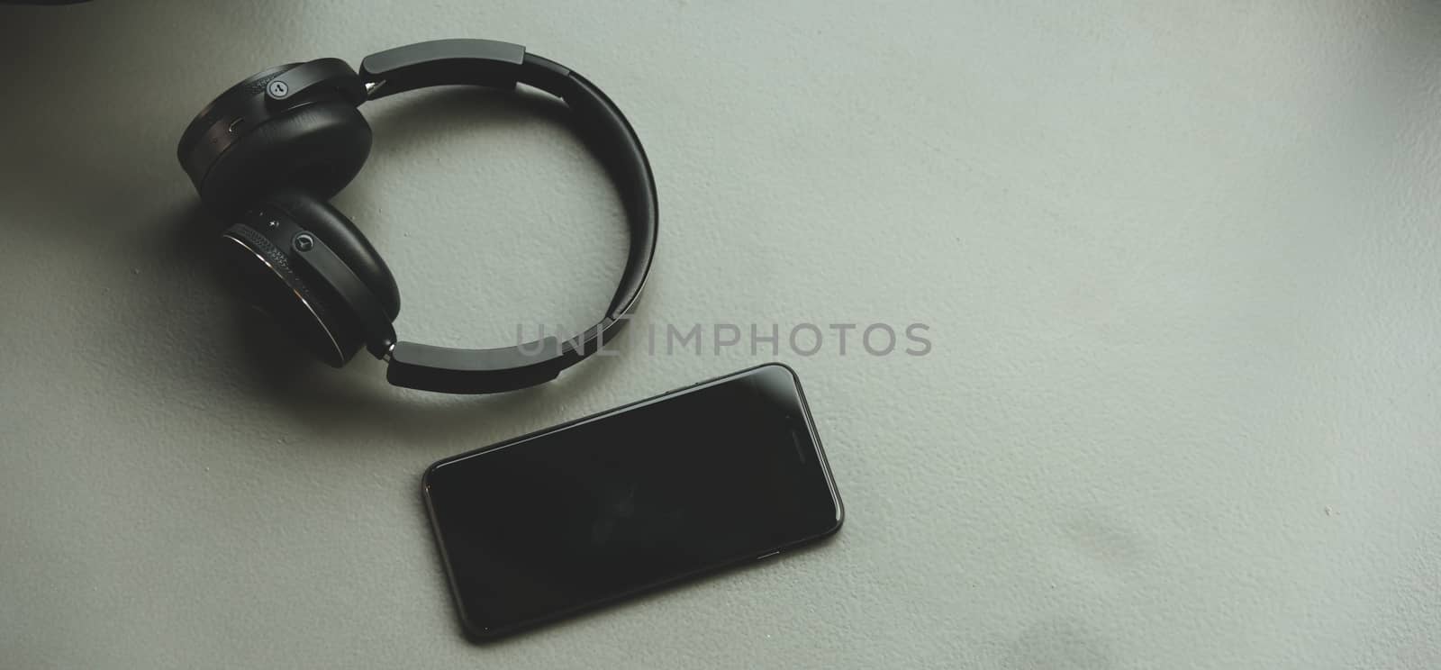 Music headphones and smart phone on rubber floor by Sorapop