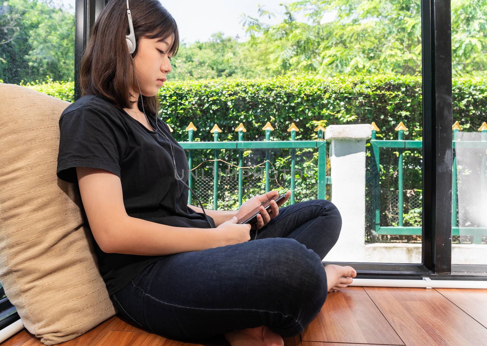 Happy teenage female  learning to the music from smartphone in room at home