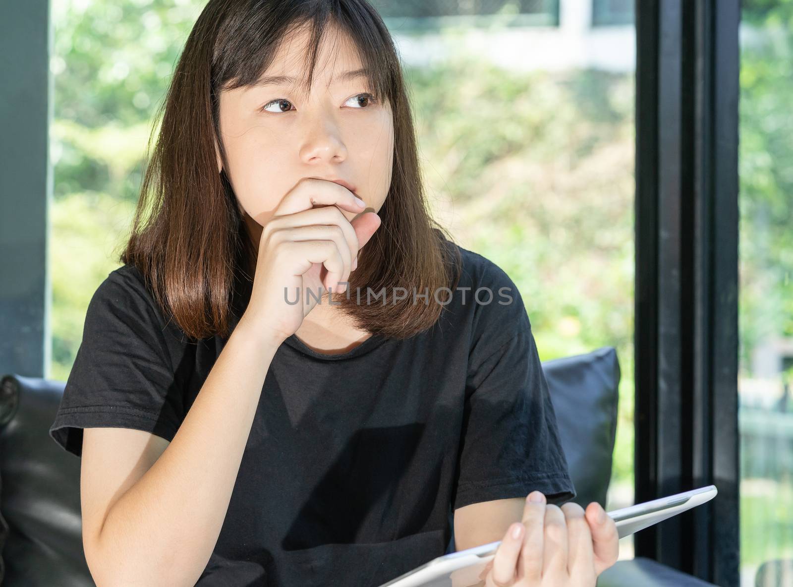 Student teenage studying online from digital tablet on the sofa at home