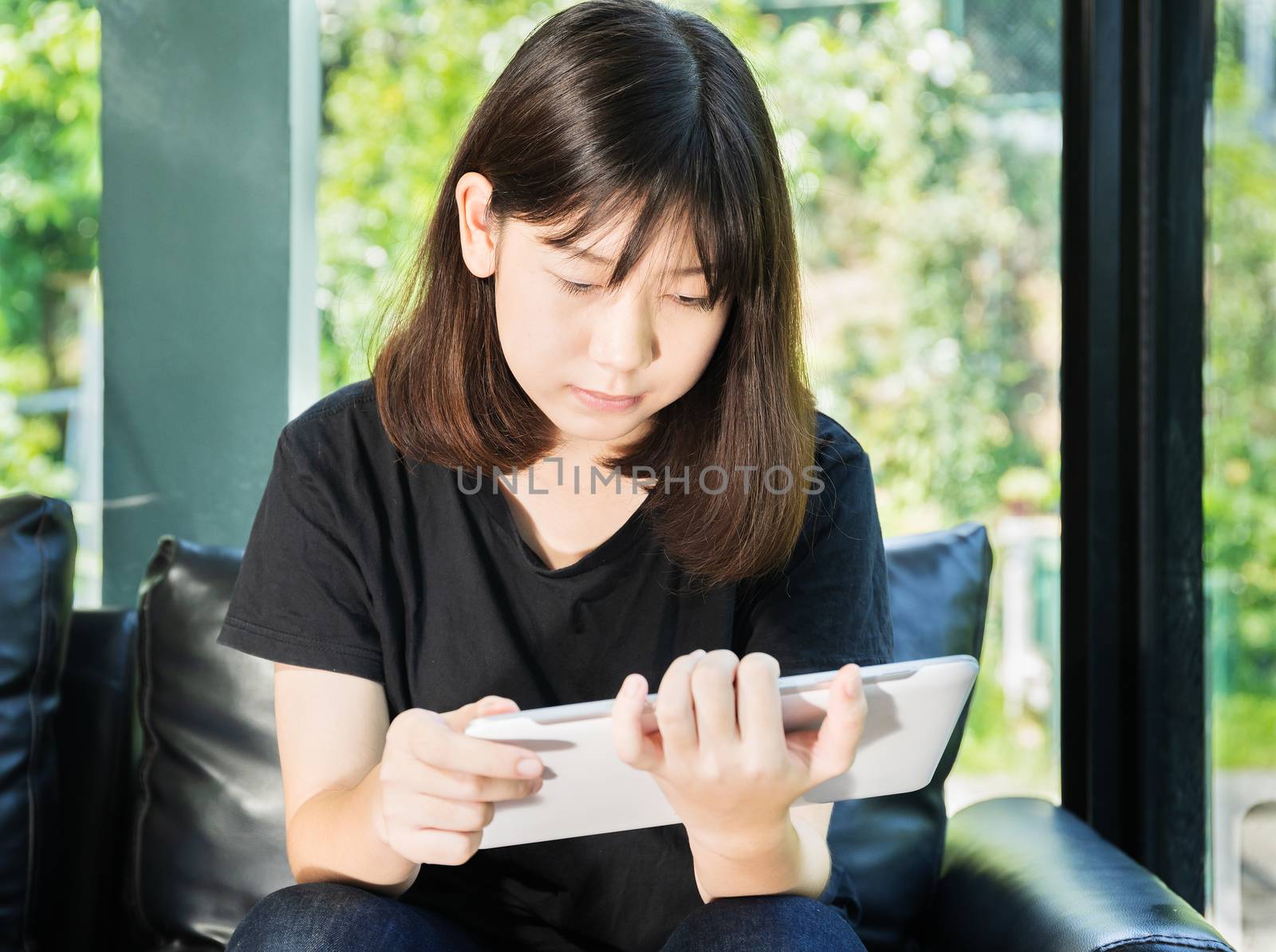 Student teenage studying online from digital tablet on the sofa at home