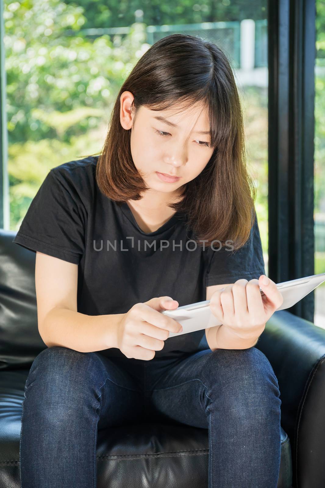 Student teenage studying online from digital tablet on the sofa at home