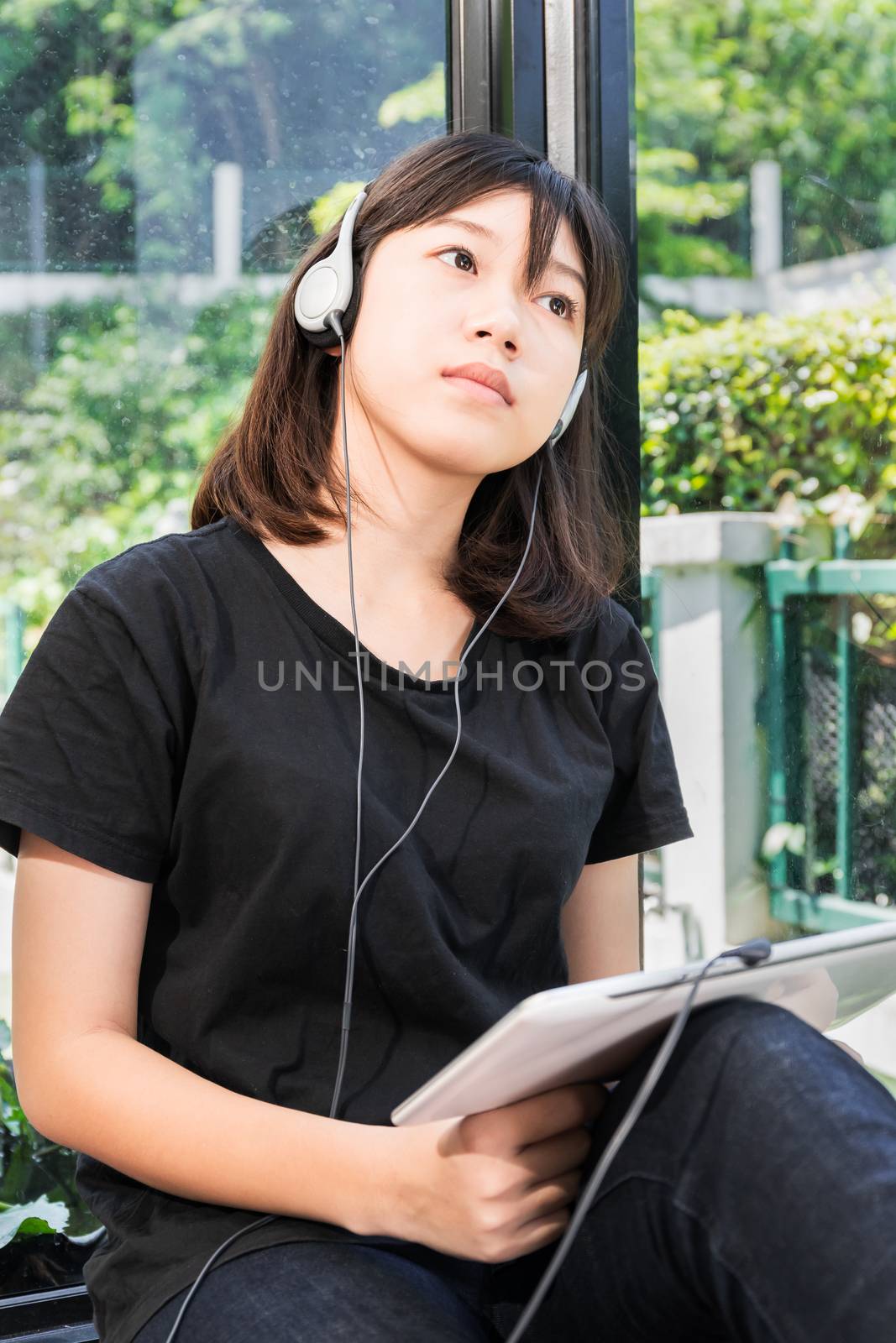 Happy teenage female  listening to the music from a digital tablet in room at home