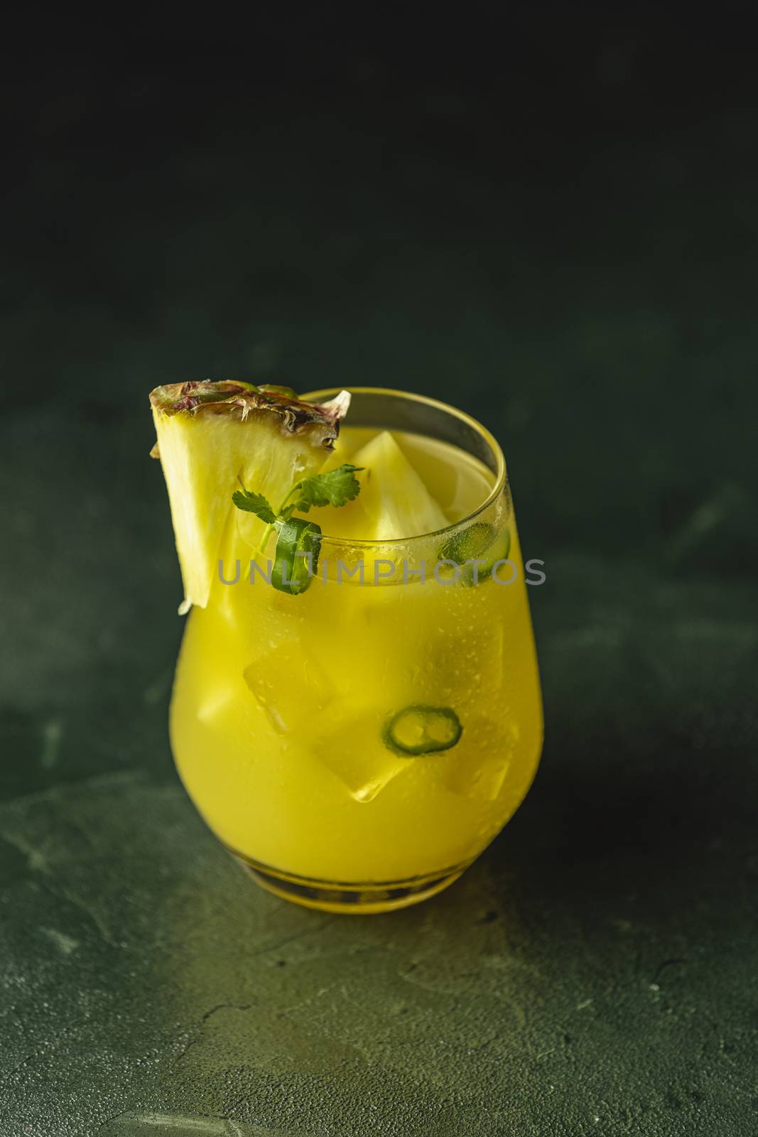 Spicy pineapple jalapeno mezcalita or margarita for Cinco de Mayo is a refreshing cocktail made with pineapple, cilantro, jalapeno and mexican distilled alcoholic beverage on dark green surface