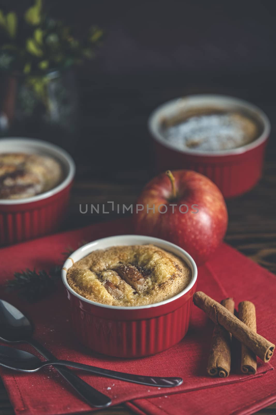 Three apple pies in ceramic baking molds with red napkin ramekin on dark wooden table. Close up, shallow depth of the field.