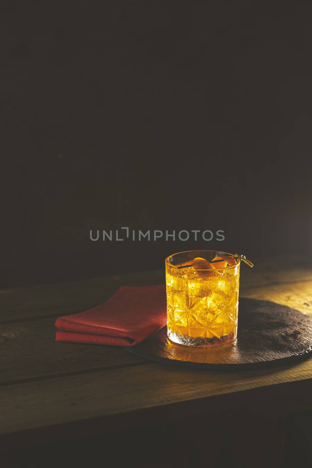 Glass of the cocktail negroni with red napkin and black stone tr by ArtSvitlyna