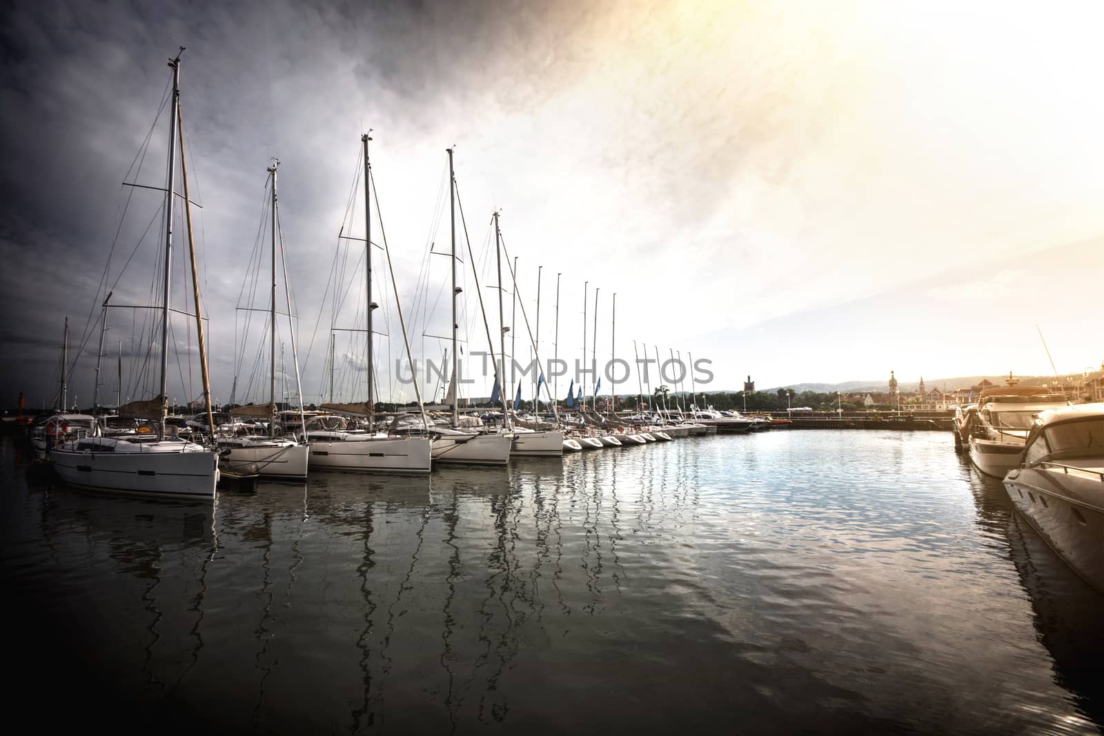 Sailboats in the port at sunset. Sail yachts in the water under beautiful summer sky.