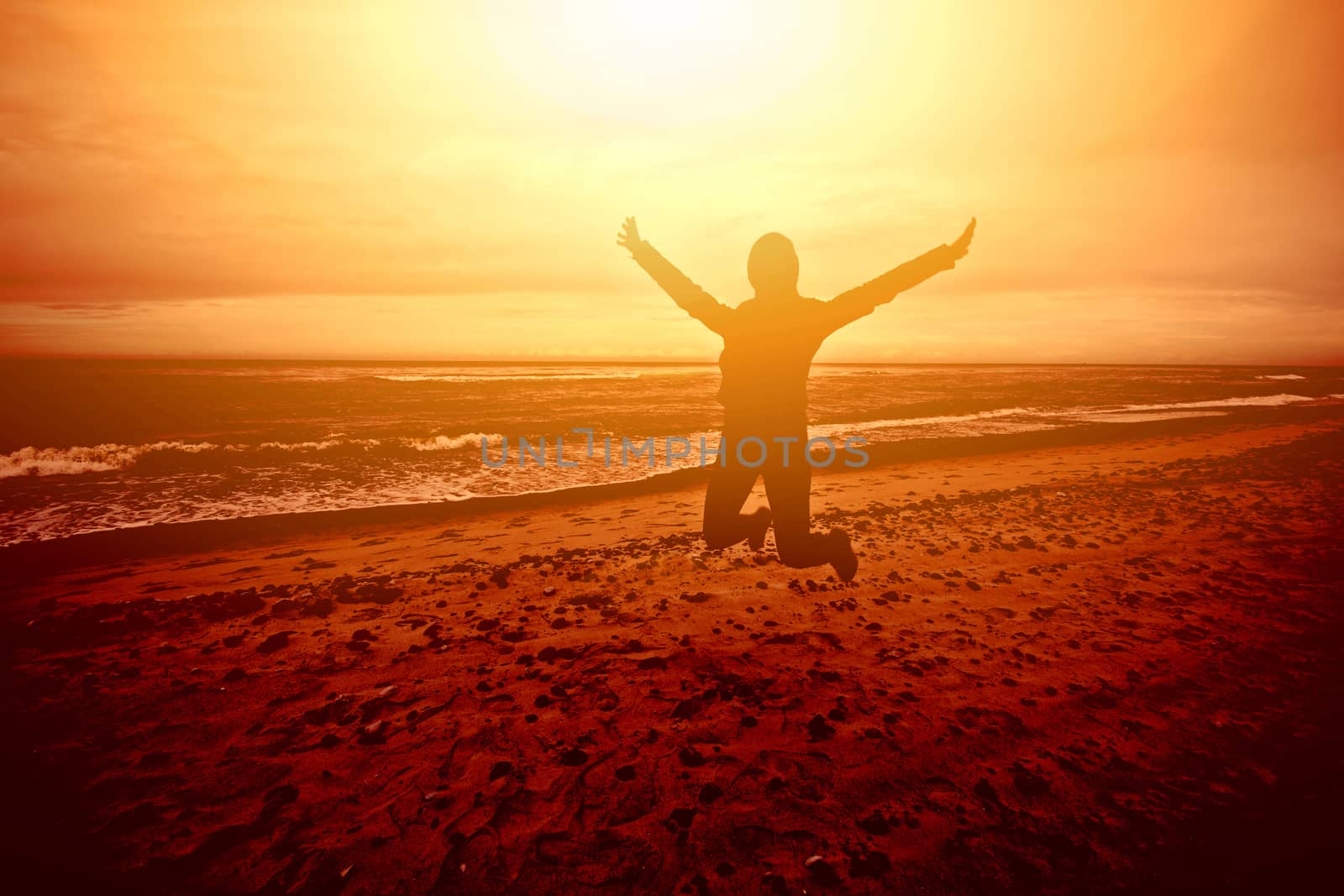Figure person jumping on the beach at sunset. Joy, freedom, happiness etc positive concept.