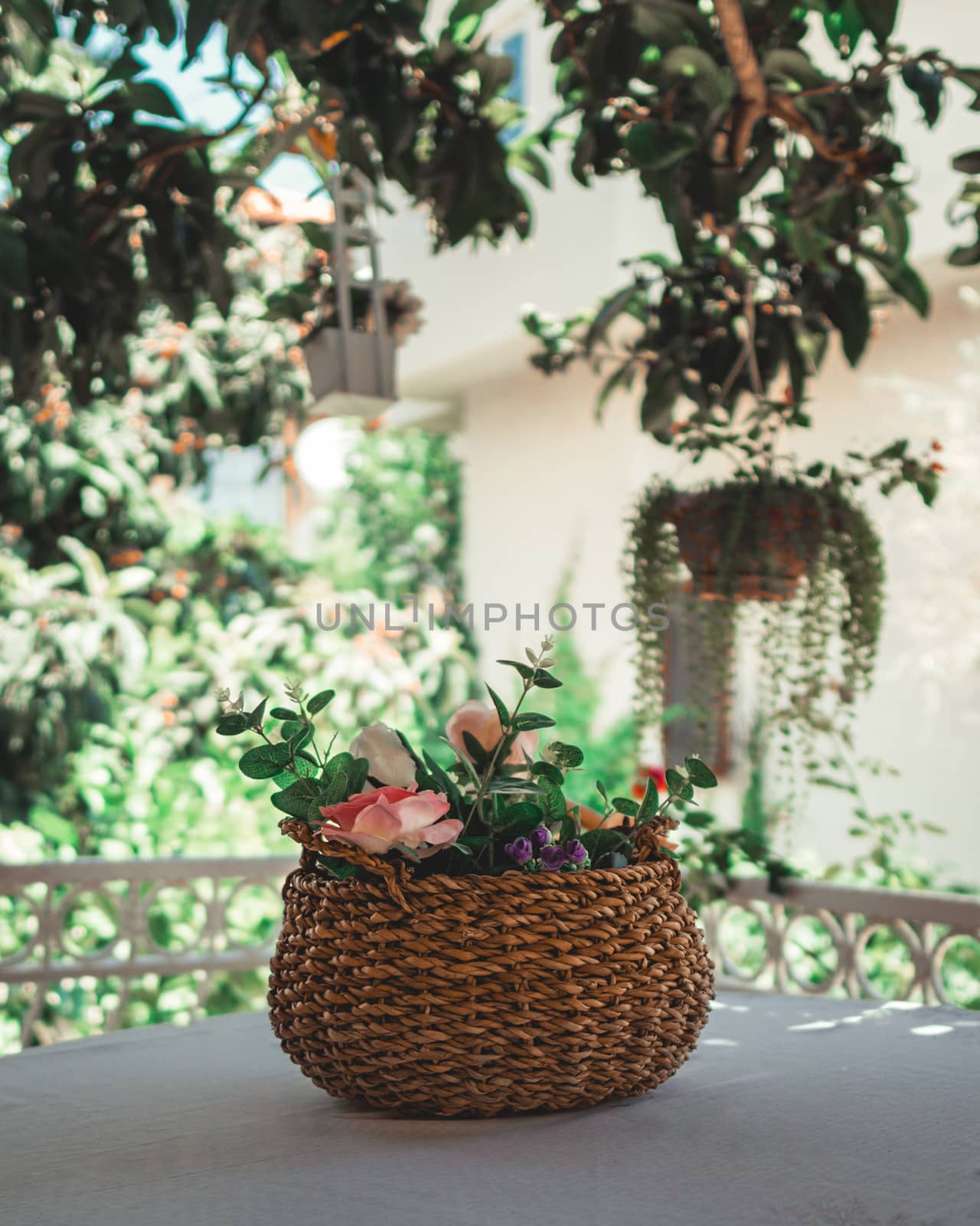 Wicker basket filled with flowers on table. by Emurado