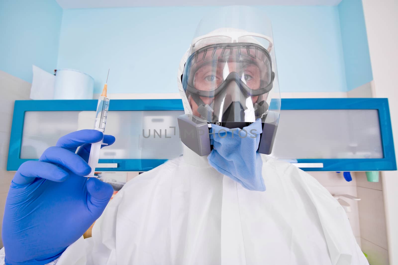 Doctor in protective suit uniform and mask holds injection syringe with vaccine. Coronavirus outbreak. Covid-19 concept.