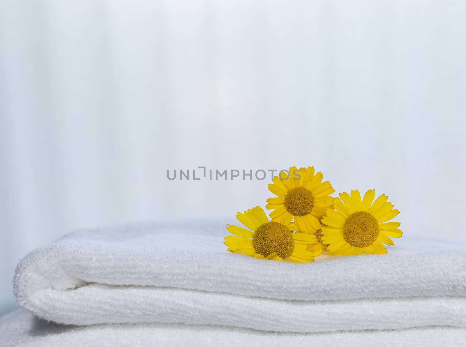 Three yellow flowers on folded towels and backlight