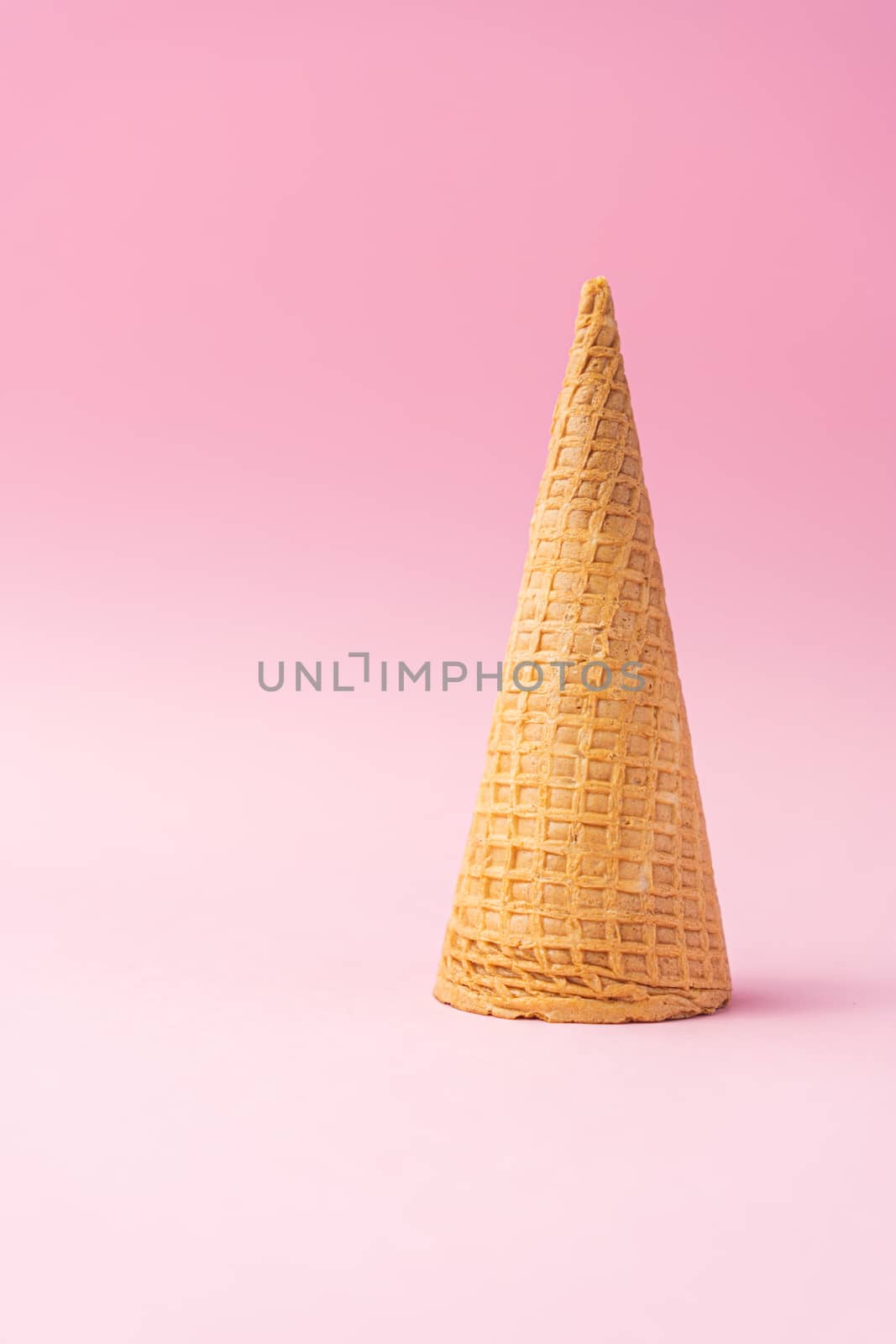 An upside down wheat flour ice cream cone on a pink background. Summer concept.