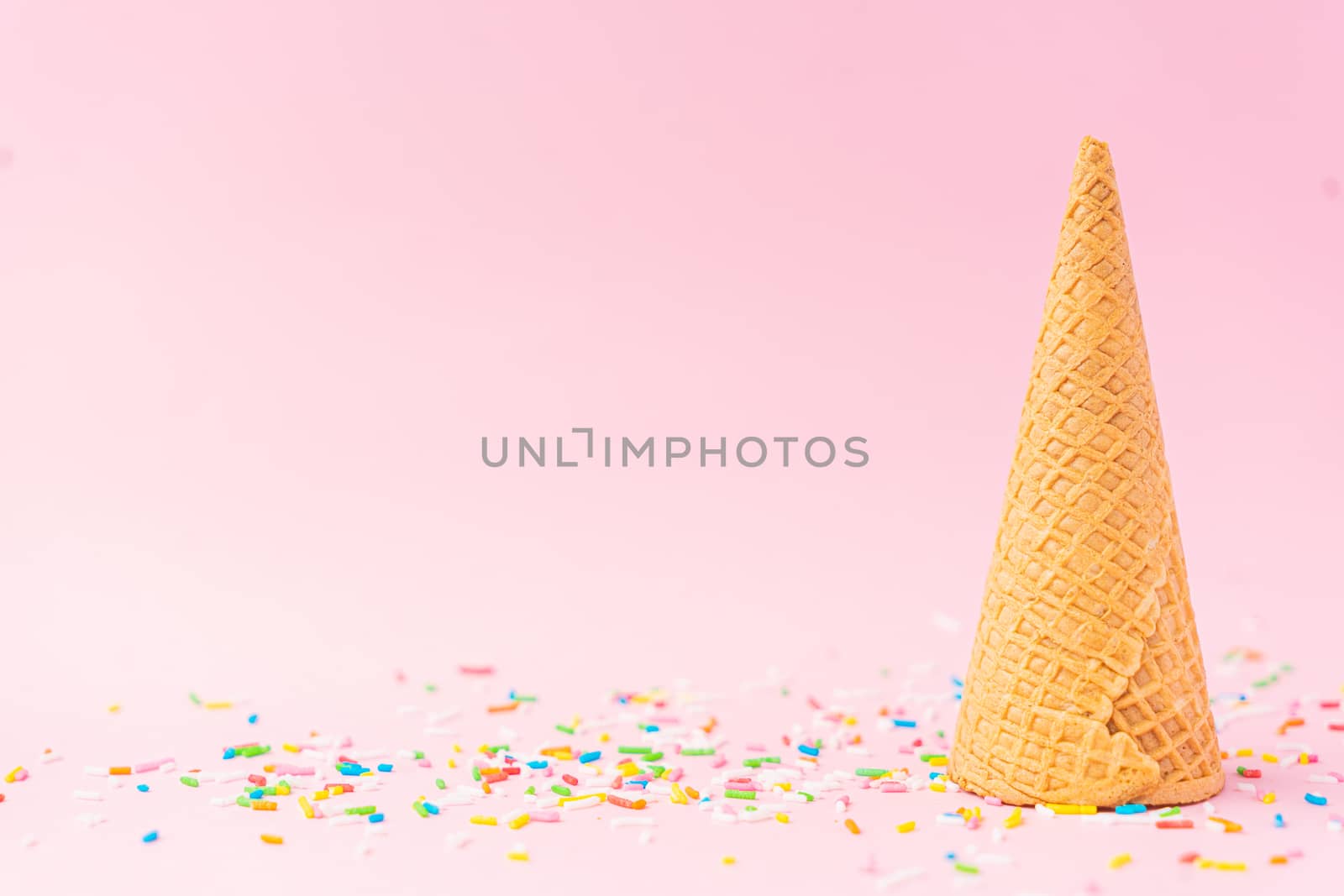 An upside down wheat flour ice cream cone located to the right on a pink background. Summer concept.