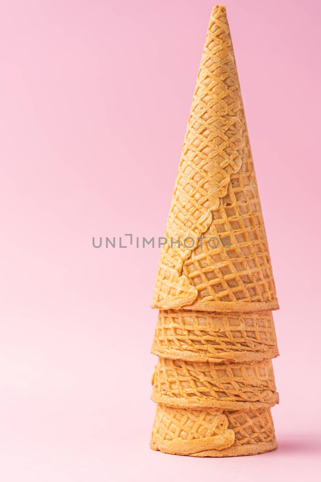 Three wheat flour ice cream cones upside down one on top of the other on a pink background. Summer concept.