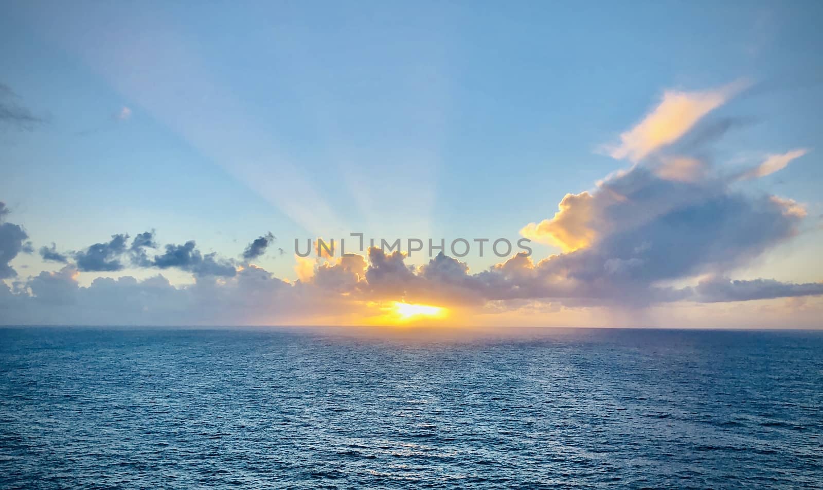 Romantic sunset over the ocean. Sunbeams passing through the clouds. Vivid colors horisontal shot