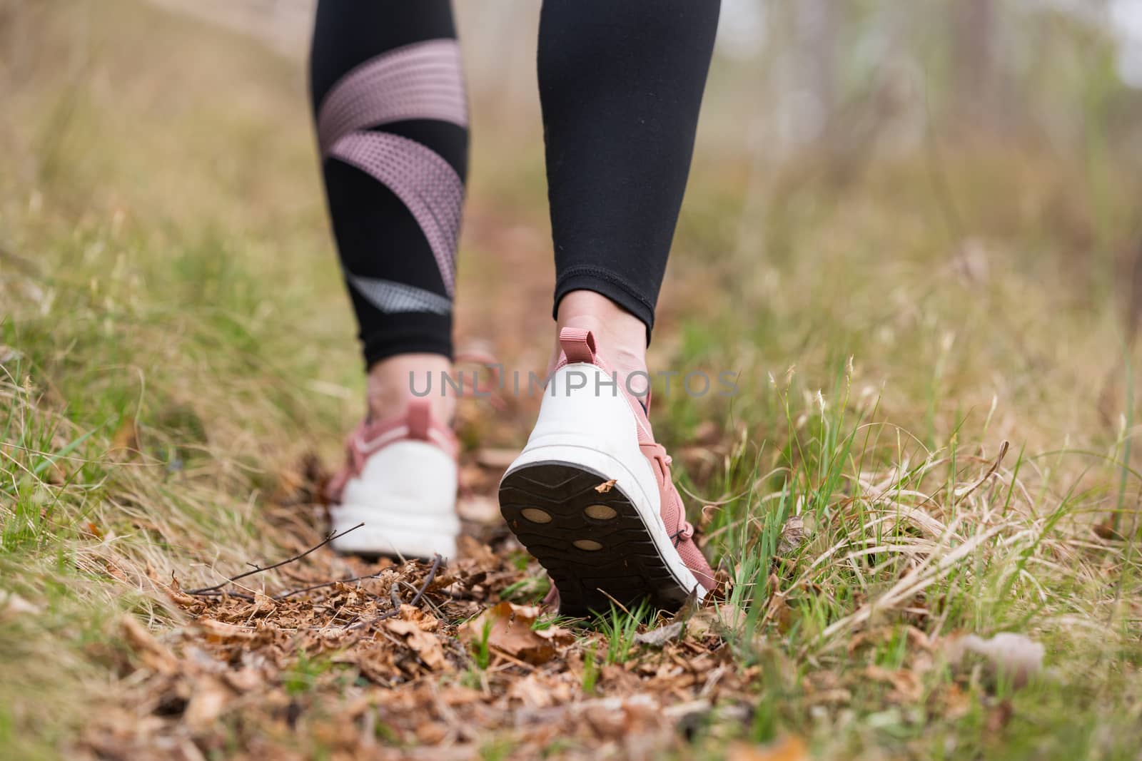 Rear close up view of female step on nature track. Young woman hiking in nature. Adventure, sport and exercise concept by kasto