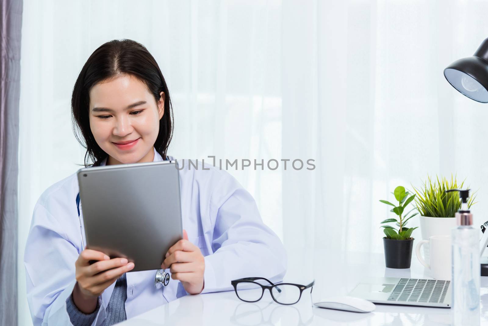 Woman doctor on front laptop computer hold modern tablet by Sorapop
