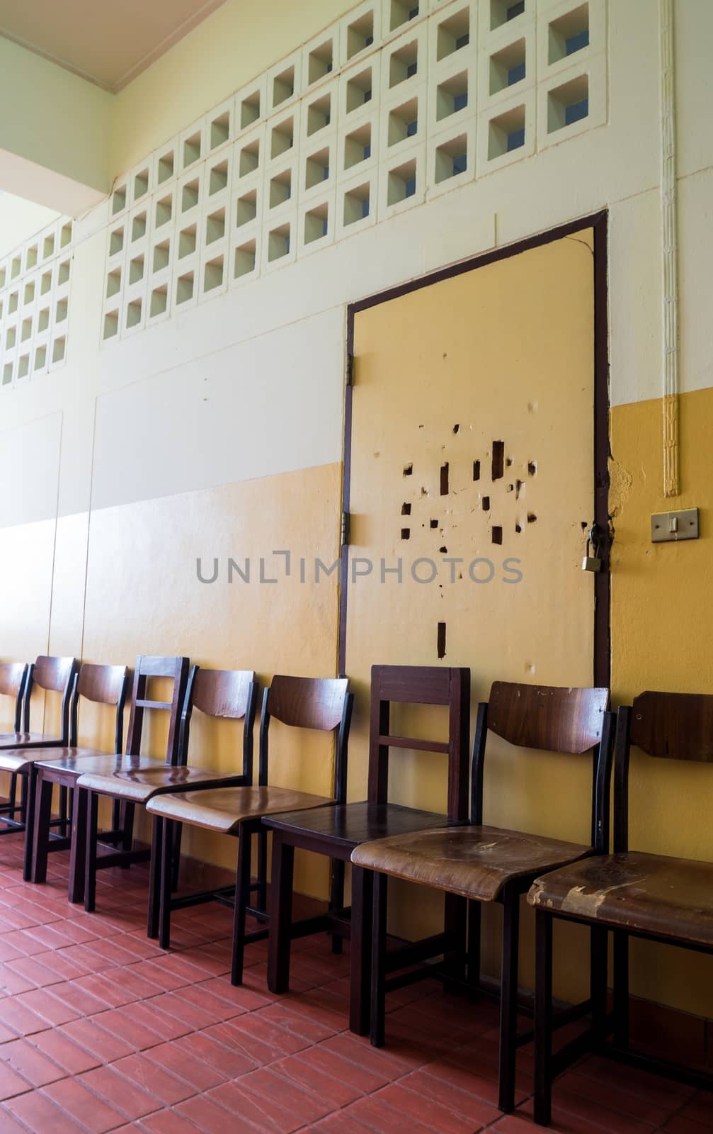 Unused student chair store in front of the broken door of an old classroom