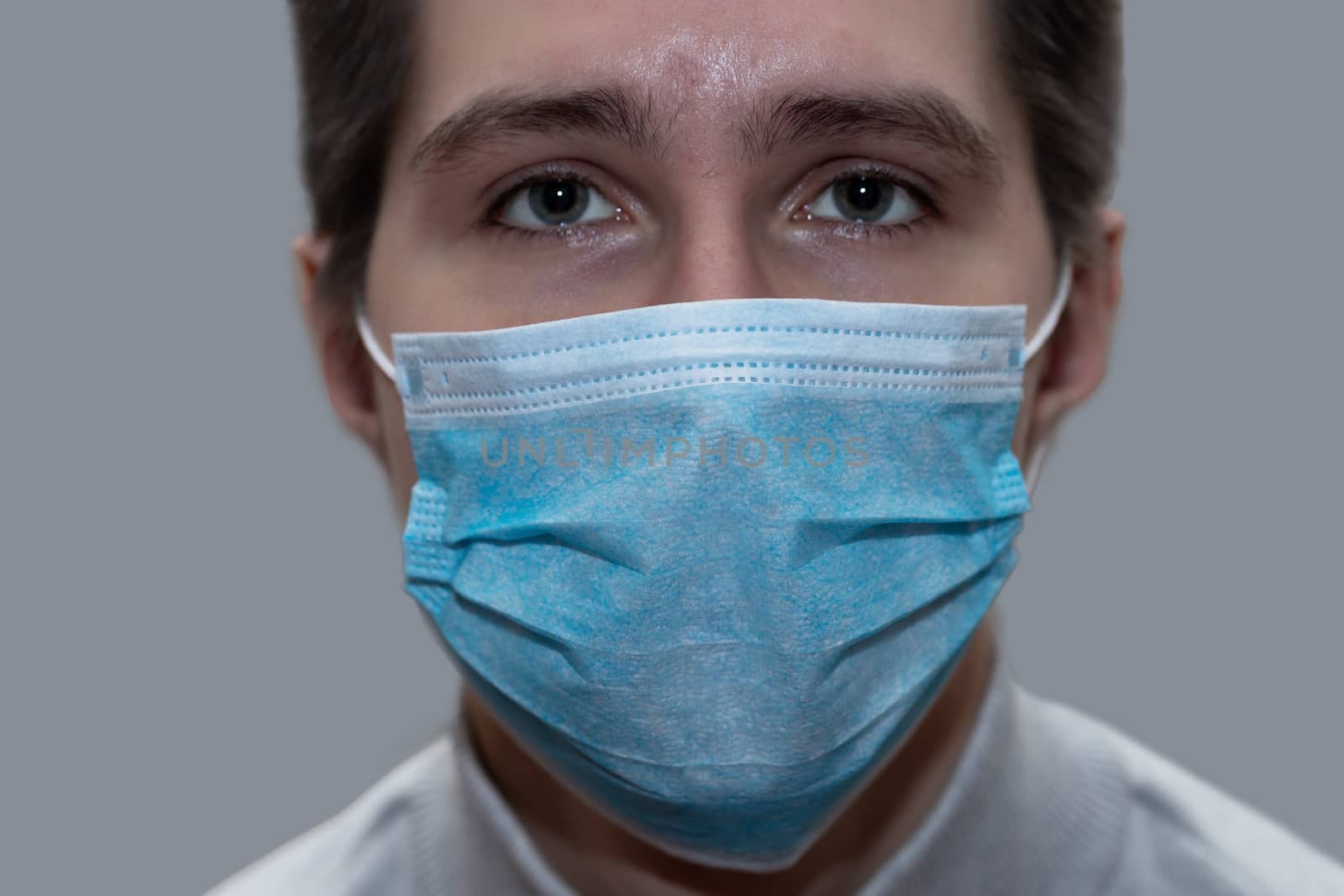 Young man in a medical mask smiles, portrait by bonilook