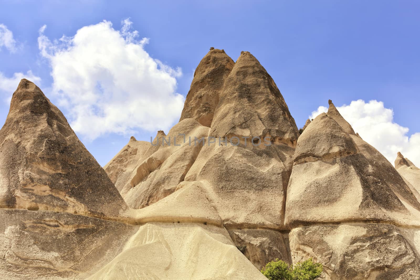 Mountain peaks of sandstone in the mountains of Cappadocia against the blue sky and white clouds.