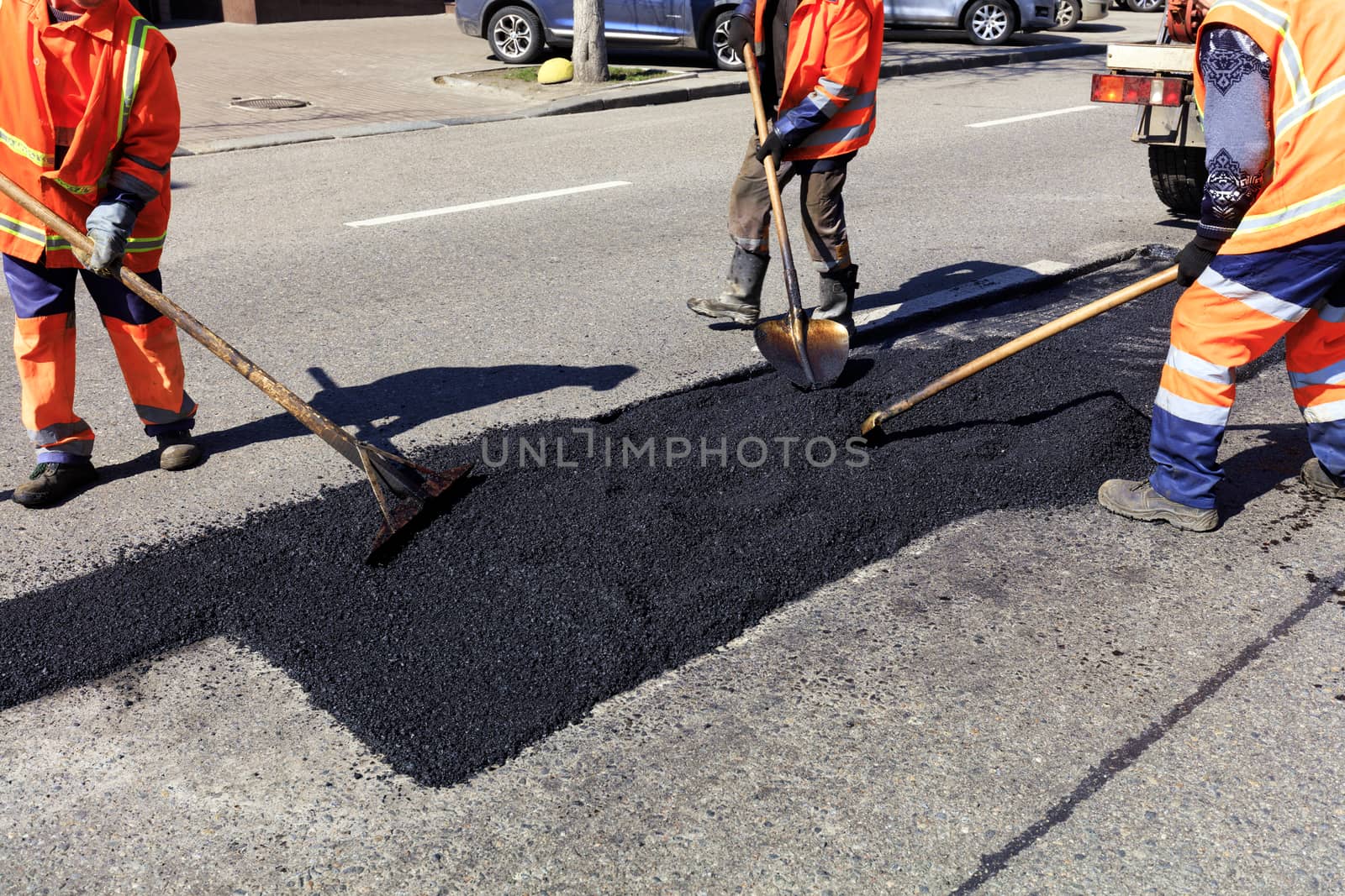 The workers' brigade clears a part of the asphalt with shovels in road construction by Sergii