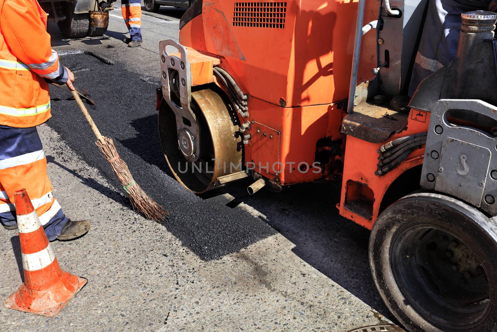 The road roller with the road service team installs asphalt and repairs the road section.