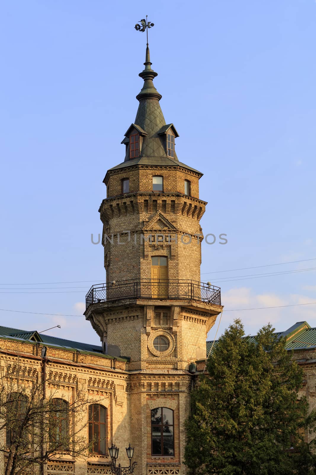 Watchtower and weathervane on the roof of an old castle against the blue sky.