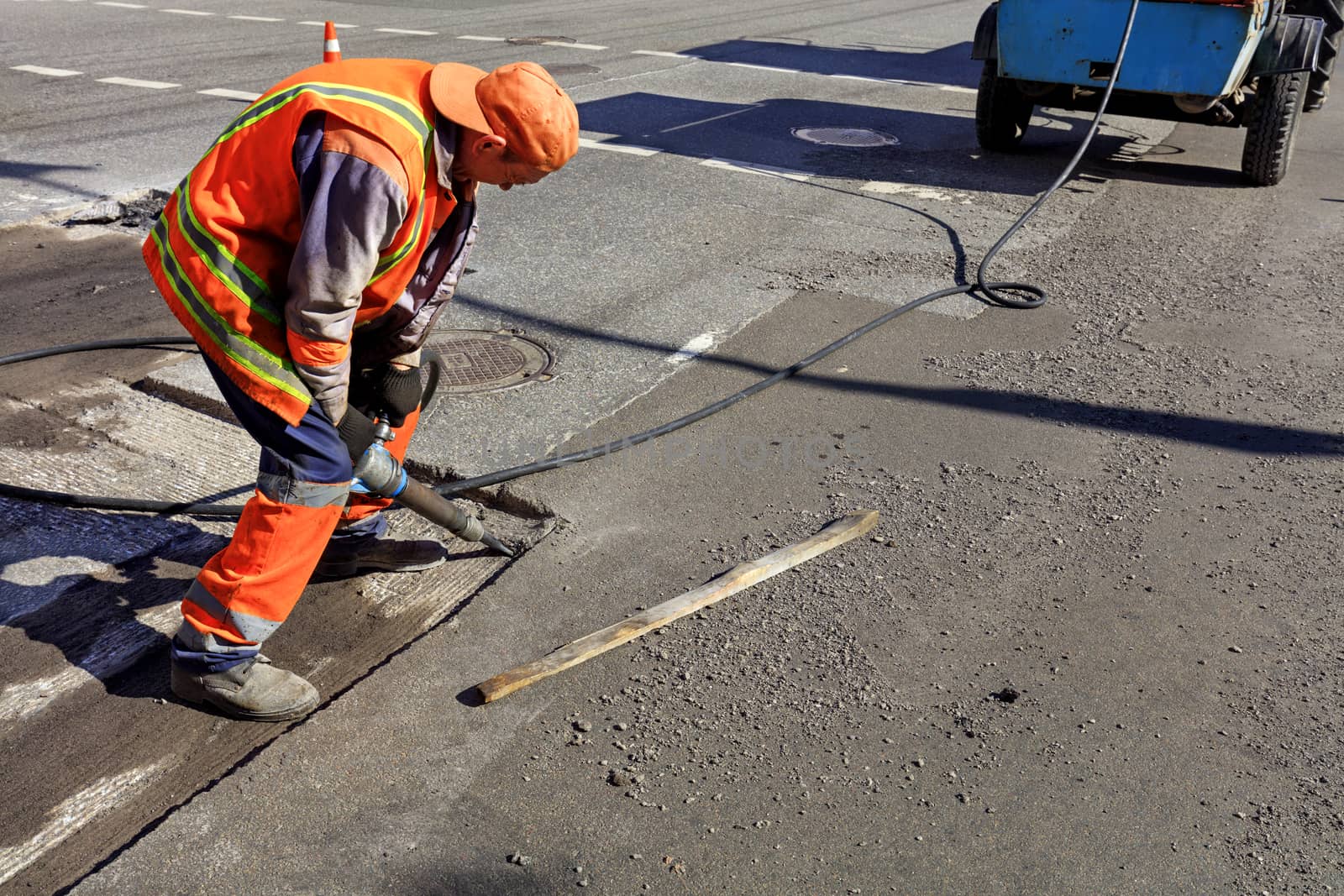 A road maintenance worker removes old asphalt with a pneumatic jackhammer during road construction.